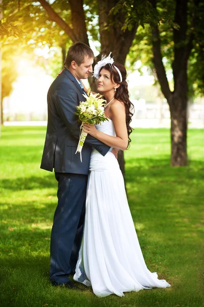 Lyckliga bruden och brudgummen i en greenl sommar park — Stockfoto