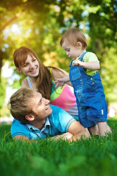 Familia feliz están caminando en el verde parque de verano — Foto de Stock