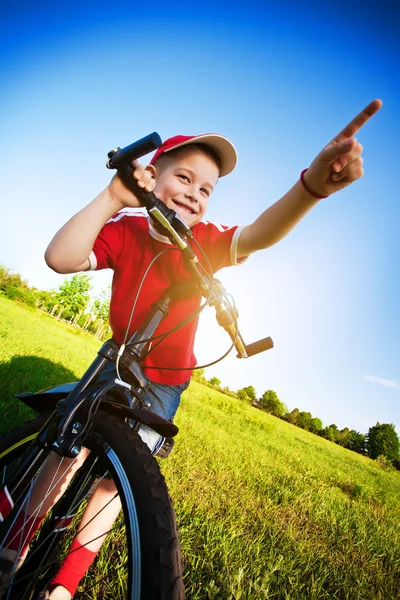 Menino em uma bicicleta aponta direção de movimento — Fotografia de Stock