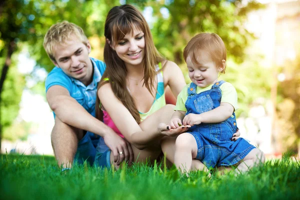 Родители с ребенком в зеленом летнем парке — стоковое фото