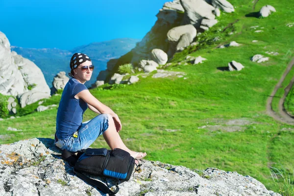 Flicka vilar sitter på klippan i bergen — Stockfoto
