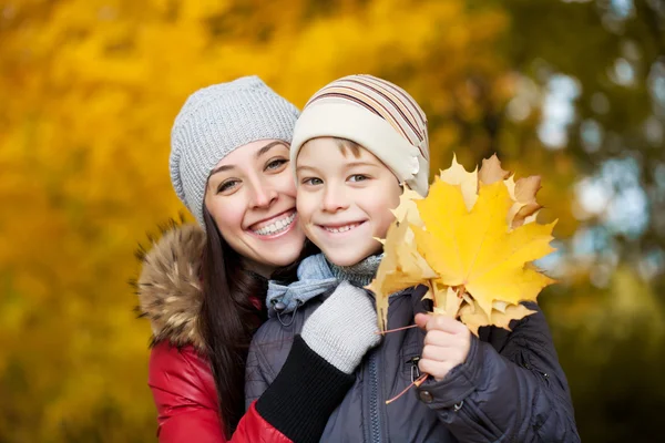 Szczęśliwa mama i syn na żółtym tle park jesień — Zdjęcie stockowe