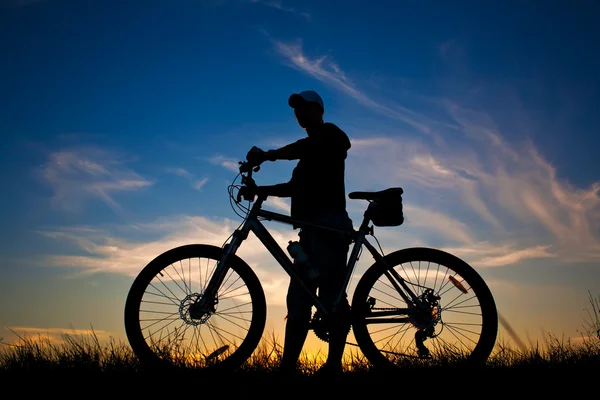 Kerékpáros egy kerékpár sziluettje a kék ég — Stock Fotó