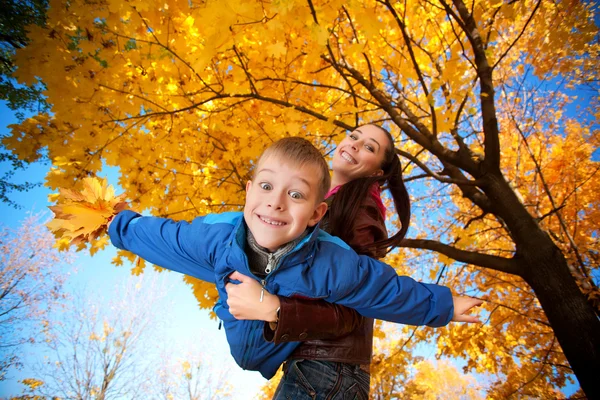 Mãe e filho felizes estão brincando no parque de outono — Fotografia de Stock