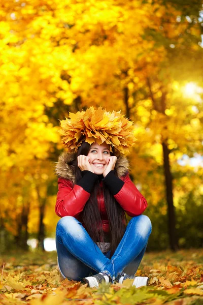 Fröhliche, fröhliche Frau im Kranz mit Herbstblättern — Stockfoto