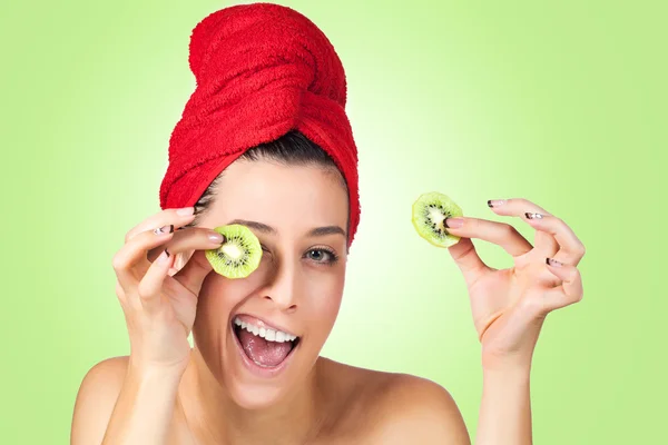 Hermosa mujer con kiwi rebanadas máscara sobre fondo verde — Foto de Stock