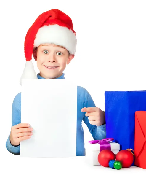 Rapaz feliz com uma folha de papel e muitos presentes de Natal — Fotografia de Stock