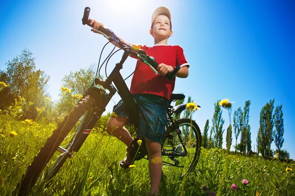 Boy with bike standing against the blue sky — Stock Photo, Image