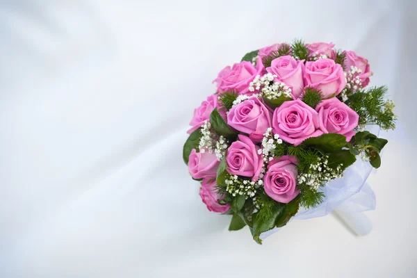 Strauß rosa Rosen auf dem weißen Hochzeitskleid — Stockfoto