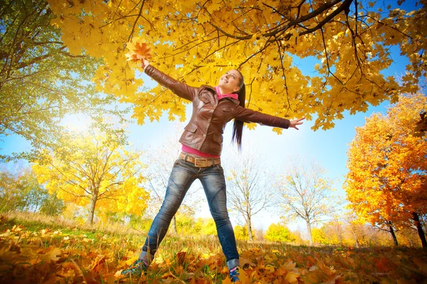 空と秋の背景上で女の子の葉します。 — ストック写真