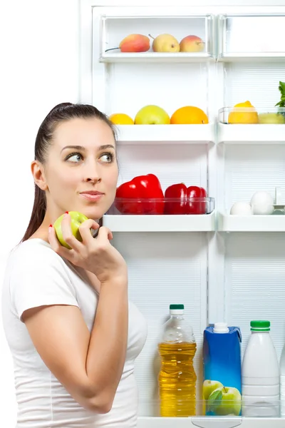 Симпатична дівчина вибирає їжу біля відкритого холодильника — стокове фото