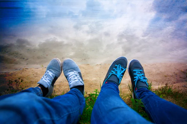 Two pairs of legs on the lake shore. sky — Stock Photo, Image