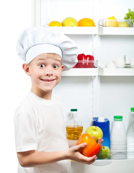 Menino cozinheiro bonito está escolhendo comida perto da geladeira aberta — Fotografia de Stock