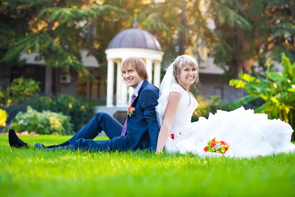 Casal feliz estão sentados na grama verde — Fotografia de Stock