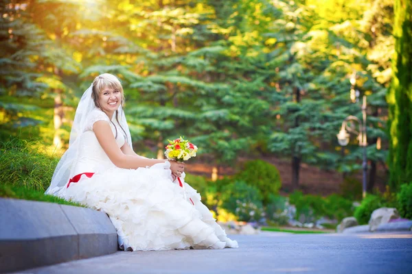 Gelukkige bruid in witte jurk zit op de stoep — Stockfoto