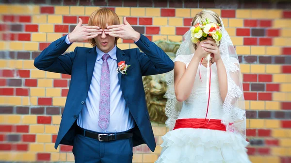 Mariée et marié sont debout près du mur à motifs — Photo