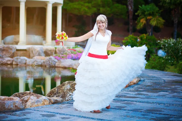 Веселая невеста гуляет по зеленому парку — стоковое фото