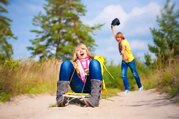 Galna pojke och flicka sledding på sommaren — Stockfoto