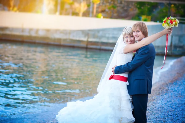Nygifta kramas på stranden — Stockfoto