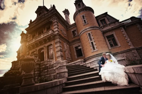 Bruden och brudgummen kramas nära det gamla slottet — Stockfoto