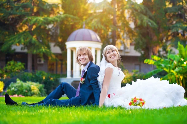 Casal feliz estão sentados na grama verde — Fotografia de Stock