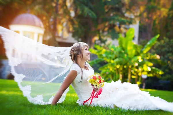 Novia en un vestido blanco está acostado en la hierba verde — Foto de Stock