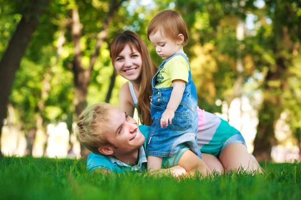 Familia en un césped verde en el parque — Foto de Stock