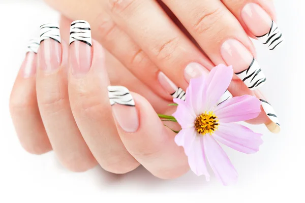 Handen met gestreepte manicure ontspannen met bloemen — Stockfoto