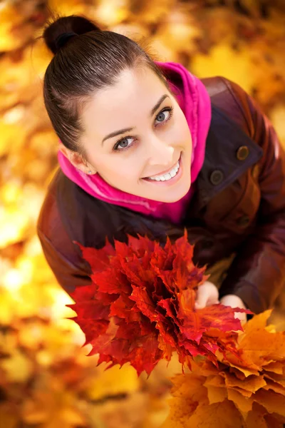 Mädchen auf einem Hintergrund aus Herbstblättern. Ansicht von oben — Stockfoto