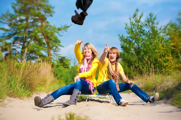 Funny couple in caps with ear flaps with sled — Stock Photo, Image