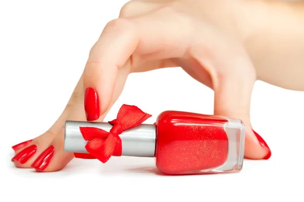 Mano de mujer con una botella de esmalte de uñas rojo —  Fotos de Stock