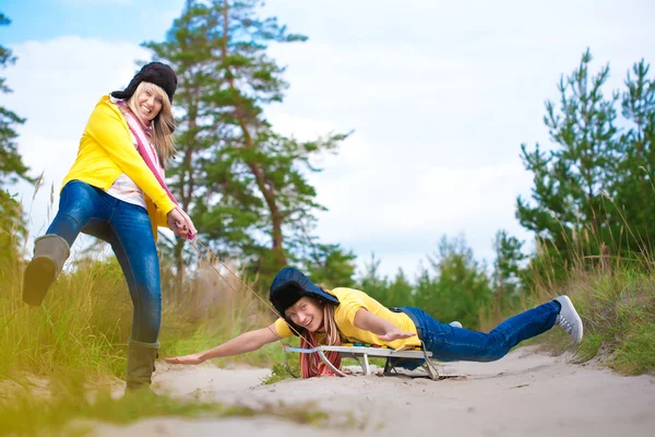 Сумасшедшие мальчик и девочка катаются на санках летом — стоковое фото