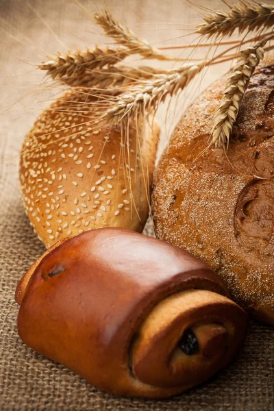 Assortment of baked bread on burlap background — Stock Photo, Image