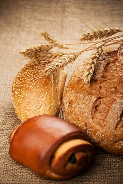 Асортимент свіжого запеченого хліба на тлі мішковини — стокове фото