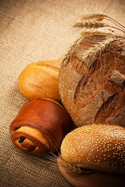 Assortiment van vers gebakken brood op jute achtergrond — Stockfoto