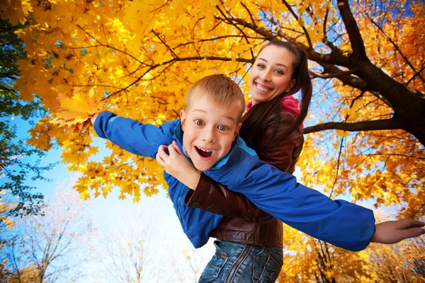 Gelukkig moeder en zoon spelen in het najaar park — Stockfoto