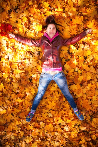 Pretty girl is lying in yellow leaves — Stock Photo, Image