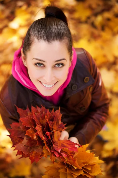Kız bir arka planda sonbahar yaprakları. Üstten Görünüm — Stok fotoğraf