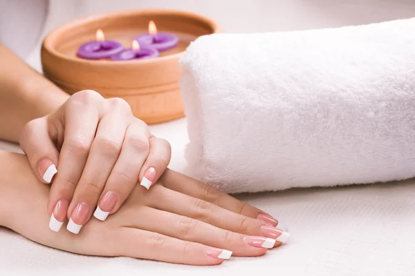 Vrouwelijke handen met aromatische kaarsen en handdoek. Spa — Stockfoto