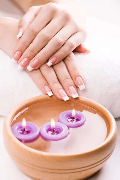 Mooie vrouwelijke handen met aromatische kaarsen en handdoek. Spa — Stockfoto