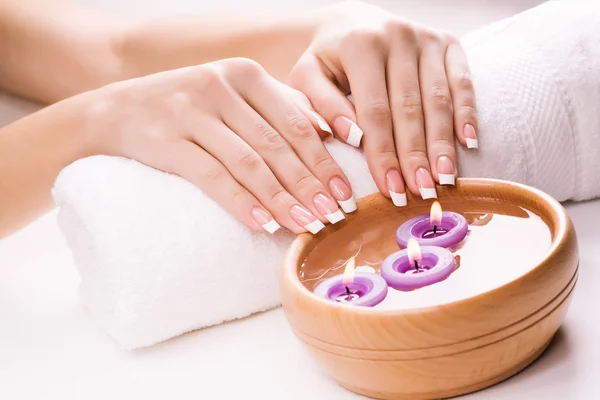 Mooie vrouwelijke handen met aromatische kaarsen en handdoek. Spa — Stockfoto