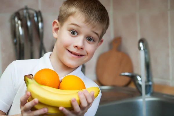 El niño está lavando fruta en la cocina. — Foto de Stock