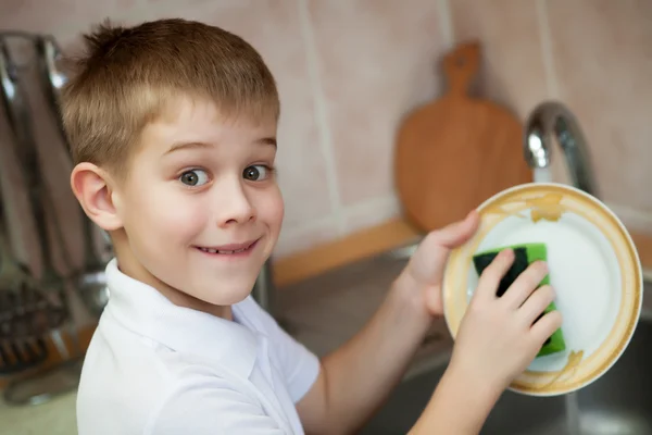Маленький хлопчик миє посуд на кухні — стокове фото