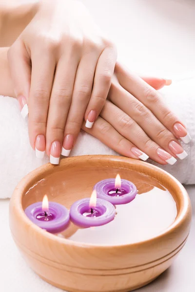 Handen met aromatische kaarsen en handdoek. Spa — Stockfoto