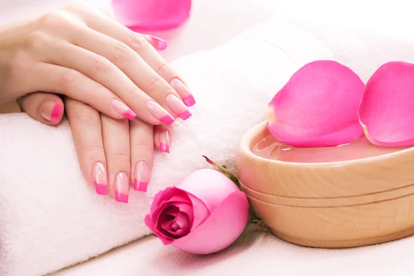 Handen met rozenblaadjes en handdoek. Spa — Stockfoto