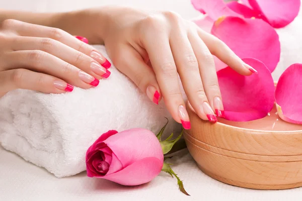 Mãos femininas com pétalas de rosa perfumadas e toalha. Spa — Fotografia de Stock