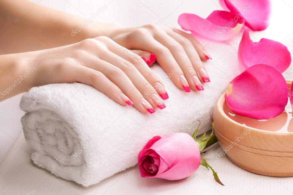 Beautiful pink manicure with fragrant rose petals and towel. Spa