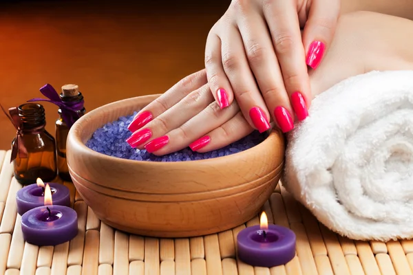 Mani femminili con candele aromatiche e asciugamano. Spa — Foto Stock