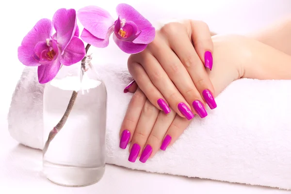 Vrouwelijke handen met geurige orchid en handdoek. — Stockfoto