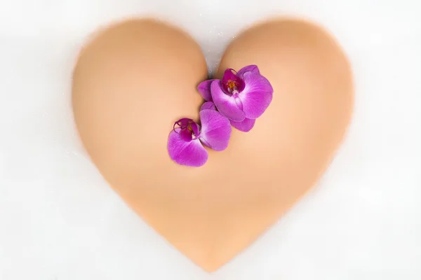 Vrouwelijke buit in de vorm van een hart met orchidee — Stockfoto